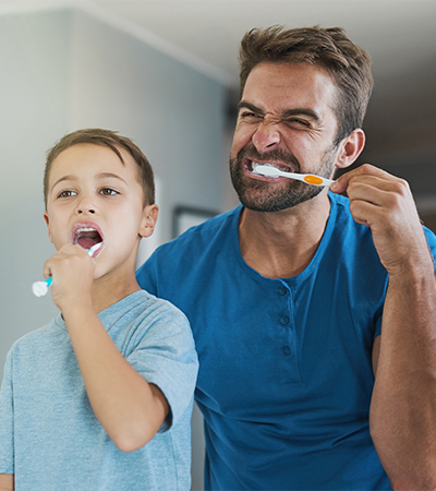 Happy father and son brushing teeth together